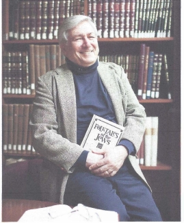 Photo Of Professor Dan Ben-Amon Holding His Book Folktales Of The Jews While Sitting In Front Of Bookcases In 2017