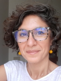 Portrait of a woman with short curly hair and glasses.